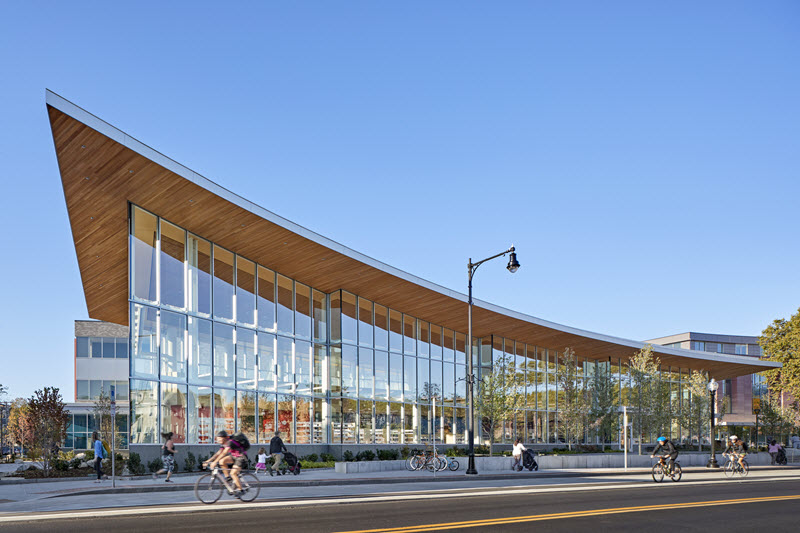 Exterior of Valente Branch Library. Bicyclists are passing by.