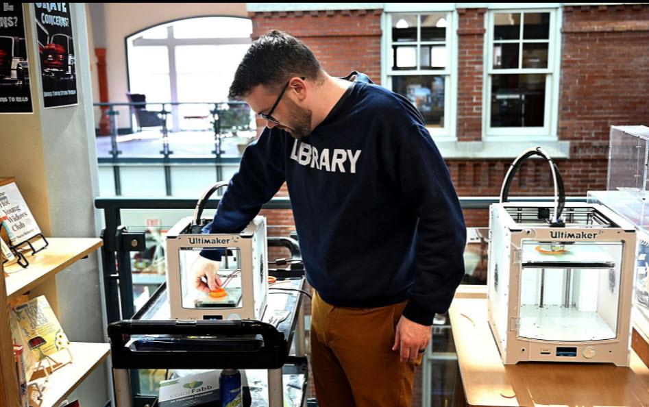Natick director Jason Homer removes a ventilator cap from a 3-D printer