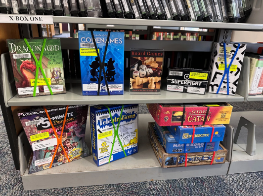 A variety of board games on display on library shelves