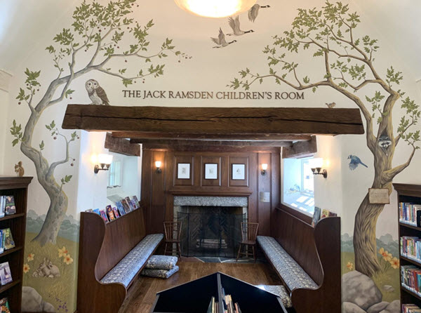 Photo of the Hills library's children's room, including depicting grass, trees, and animals. 